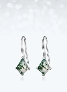 Macro view of diamond-shaped moss agate earrings with silver hooks and natural green patterns