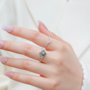 Detailed view of moss agate ring set with V-shaped diamond band on a model's hand