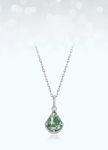 Macro shot of fan-shaped green moss agate pendant with detailed silver engraving