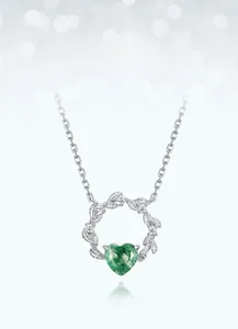 Close-up of heart-shaped green moss agate pendant with silver leaf wreath and zircons
