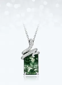 Macro shot of silver snake-shaped pendant wrapped around green moss agate stone