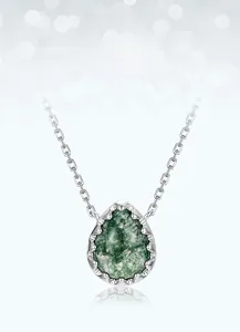Macro detail of teardrop moss agate pendant with sparkling crystal halo on silver chain