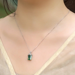 Close-up of green moss agate pendant with silver snake detail on elegant silk dress
