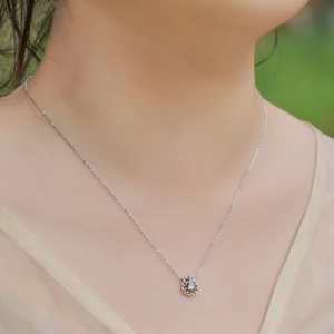 Pear-shaped green moss agate pendant in S925 silver worn by a model in nature