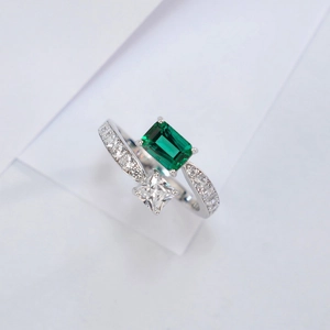 Detail of S925 silver ring featuring emerald cut green stone and princess cut diamond