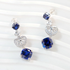 Macro shot of deep blue square-cut gemstone earrings with silver heart accents