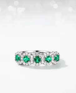 Macro shot of silver ring with five emerald lab-grown stones in a row with zircon halo