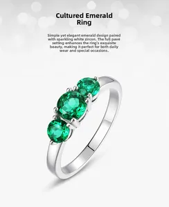 Macro view of lab-grown emerald ring showing three round green stones in silver setting