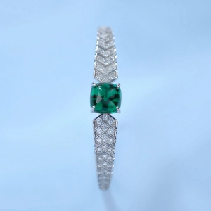 Macro detail of S925 silver chevron bracelet with emerald center and pavé diamonds