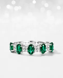 Détail de cinq émeraudes de laboratoire ovales et zircons sur bague en argent