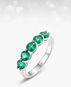 Macro detail of S925 silver ring with five claw-set green lab-grown emeralds