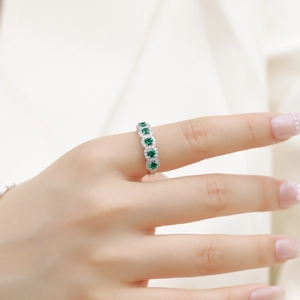 Elegant S925 silver ring with five halo-set green emerald stones worn by a model