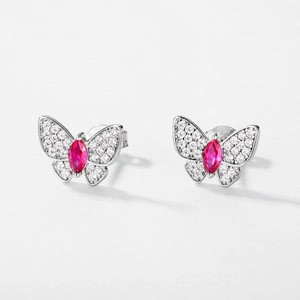Macro shot of silver butterfly earrings with red gemstone and sparkling pavé diamonds