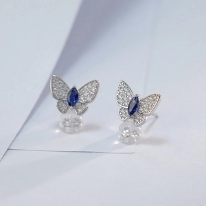 Macro view of butterfly stud earrings with blue marquise gem and pavé crystals