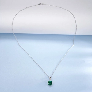 Detailed view of round green emerald pendant in six-claw silver setting necklace