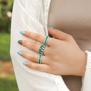 Detailed view of three silver rings with marquise emeralds and diamonds on a model's hand