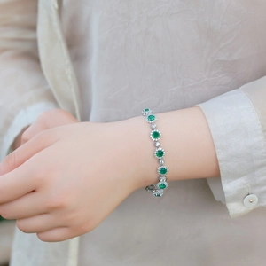 Elegant silver bracelet with emerald-green gemstones and sparkling floral halo settings