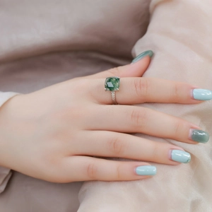 Square green moss agate ring with textured silver band on champagne silk background