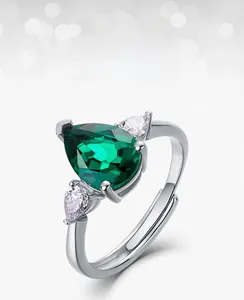 Detailed side view of pear-cut emerald ring with silver adjustable band and white zircons