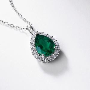 Elegant pear cut emerald pendant necklace with halo diamond setting on silver chain