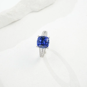 Macro detail of silver ring featuring a blue cushion-cut stone and side diamonds