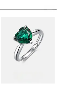 Macro shot of silver ring featuring heart-cut green emerald with adjustable open band