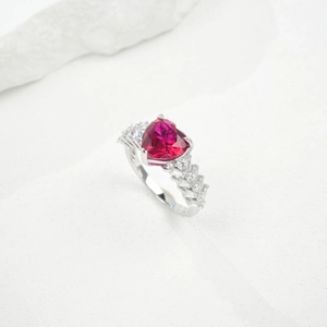 Close-up of heart-shaped ruby silver ring with shimmering baguette side stones