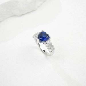 Detail of heart-shaped blue sapphire ring with baguette and round side diamonds