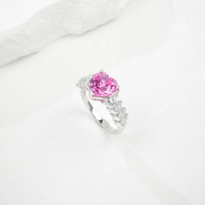 Close-up of heart-cut pink sapphire ring with tapered baguette accents on rock texture
