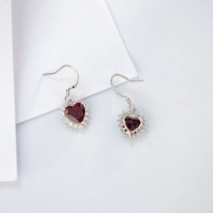 Macro shot of S925 silver hook and red heart-shaped gemstone earring with halo diamonds