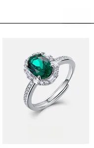 Macro shot of oval emerald gemstone ring with halo diamonds and adjustable S925 silver band