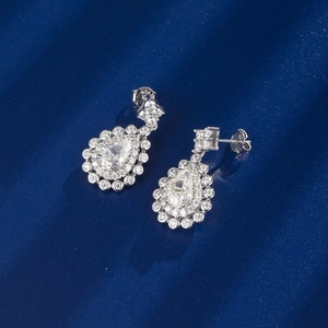 Macro shot of S925 silver stud earrings featuring pear-cut emerald gems and diamonds