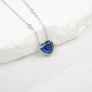 Detail of silver S925 necklace featuring a blue heart-shaped lab emerald gemstone