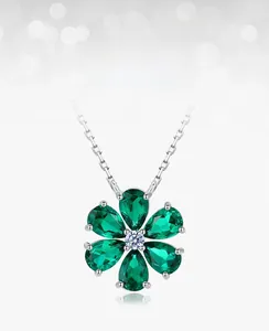 Macro view of flower pendant featuring pear-cut emerald and sparkling white zircon center