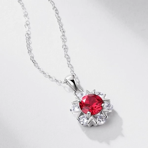 Floral sterling silver necklace with a central ruby and sparkling zircons on grey surface