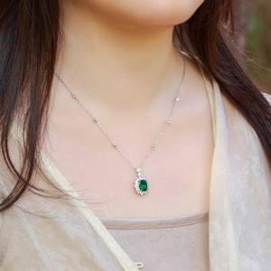 Vintage oval emerald pendant necklace with S925 silver diamond halo on a model's neck