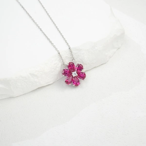 Macro view of flower pendant featuring pear-cut pink gemstones on silver chain necklace
