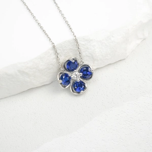 Macro detail of silver four-leaf clover pendant with faceted blue stones and center gem