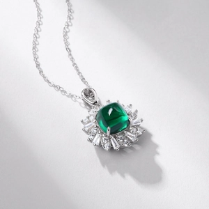 Macro shot of cushion-cut emerald pendant with sunburst diamond halo on silver chain