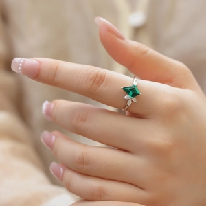 S925 silver ring with kite-cut emerald and side accent stones on a model hand