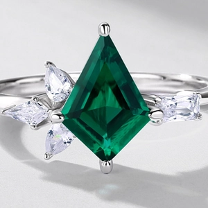 Kite-cut emerald green gemstone ring in silver setting with side accent stones