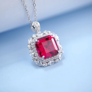 Gros plan d'un pendentif en pierre taille émeraude entouré de diamants sur chaîne en argent