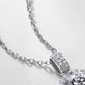 Classic 1-carat round halo moissanite pendant in S925 sterling silver on gray texture