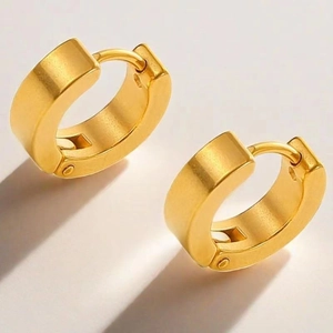 Macro shot of chunky gold hoop earrings with hinged closure and architectural shadows