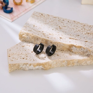 Minimalist matte black stainless steel hoop earrings for men on stone display blocks