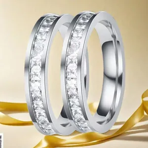 Close-up of two silver rings with channel-set square diamonds on a beige silk ribbon