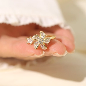 Close-up of a gold flower ring with teardrop zircons on a hand with soft lighting