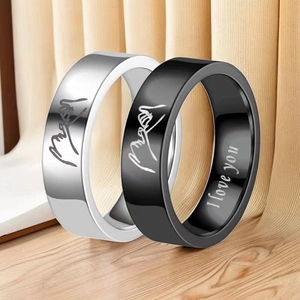 Macro view of couple rings in black and silver with engraved promise hand gesture