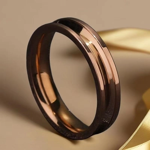 Bague en acier titane poli bronze et or rose posée sur un ruban de satin jaune