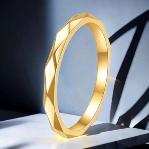 Detail of a thin gold stainless steel ring with a faceted geometric polished finish